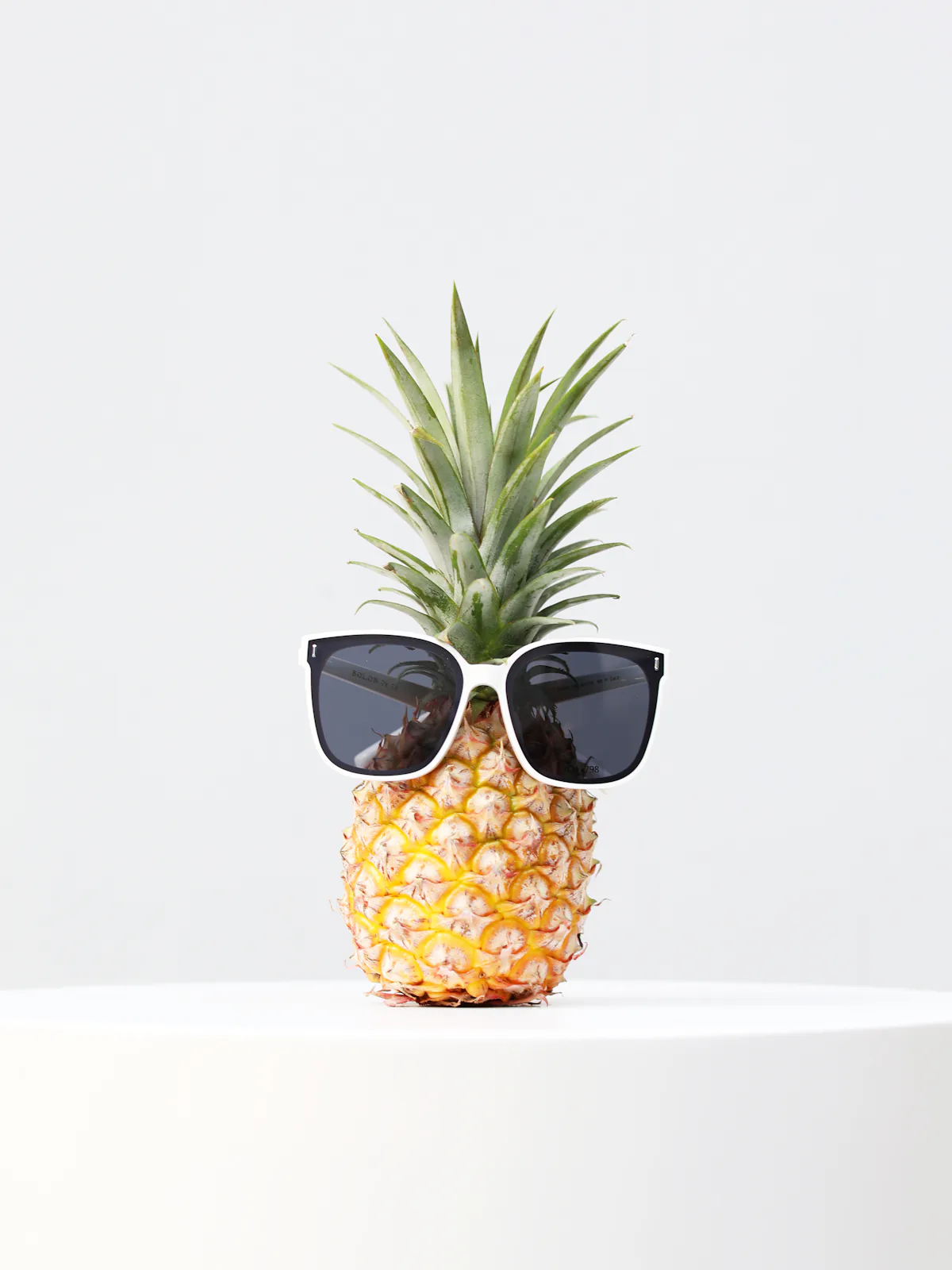 Pineapple wearing black sunglasses on a white pedestal